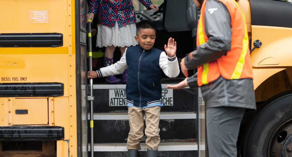 Boy high-fiving bus driver