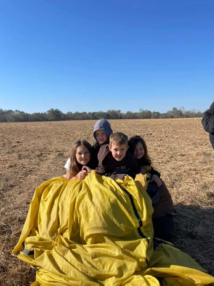 Group of kids posing inside of hot air balloon gondola.